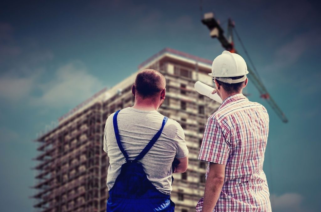 Two workers pointing at building under construction