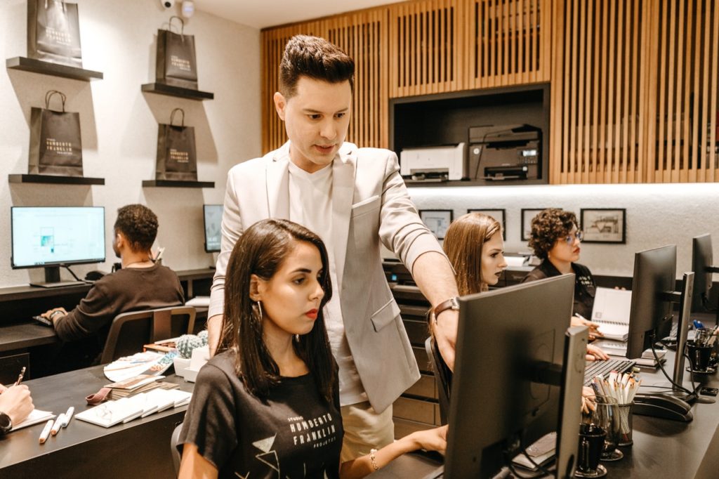 Man teaching woman in front of computer