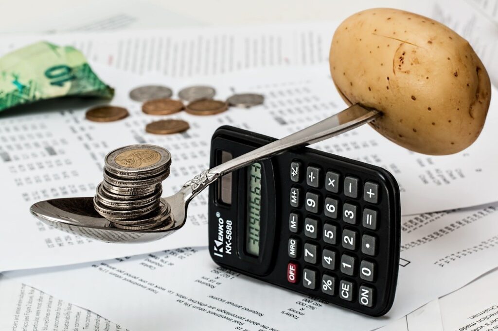 Photo of coins and potato balancing on a calculator