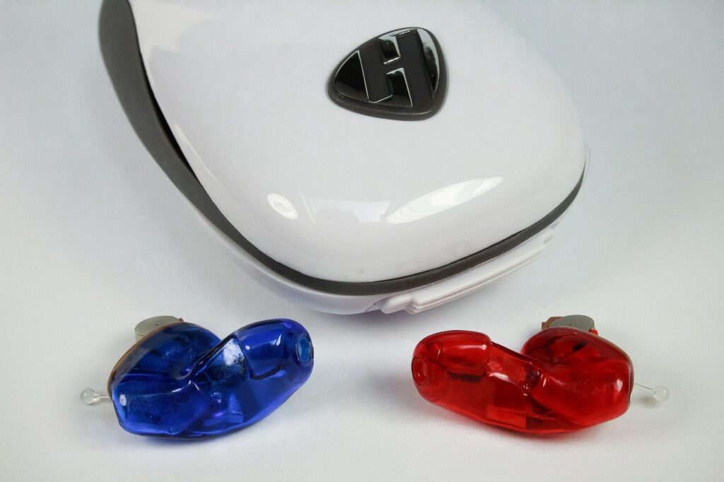A red and blue hearing aid in a hand