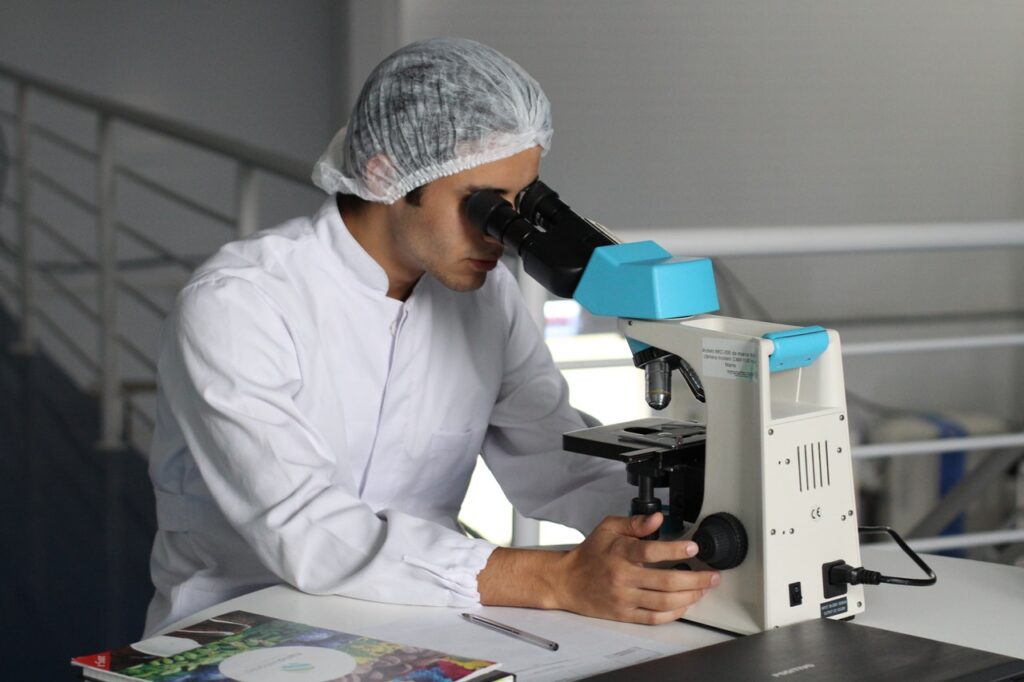 Biomedical engineer looking into microscope