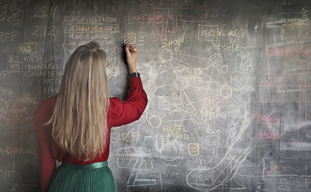 Woman in red top writing on chalkboard