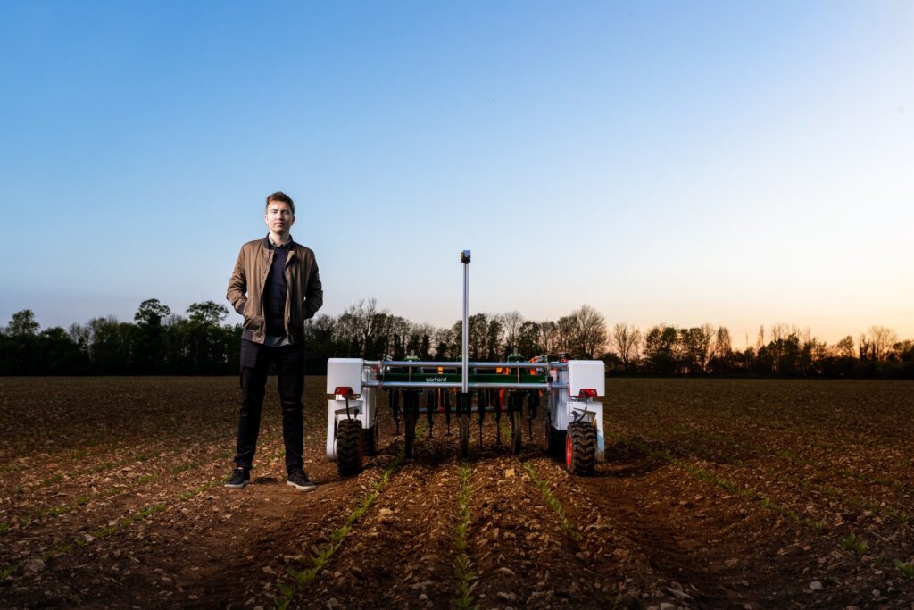 Engineer standing in field beside a robot plough