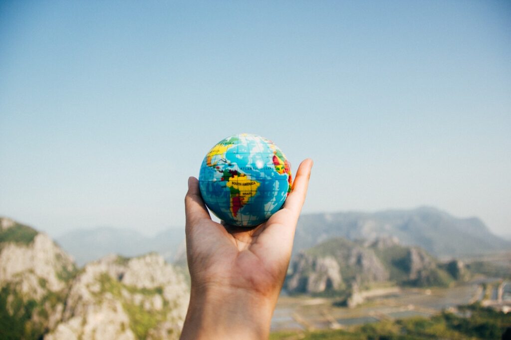 Hand holding globe in front of mountains
